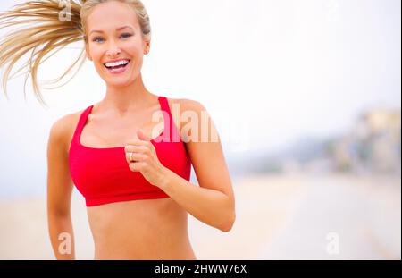 Courir est un mode de vie. Photo d'une jeune femme qui fait du jogging près de la plage. Banque D'Images