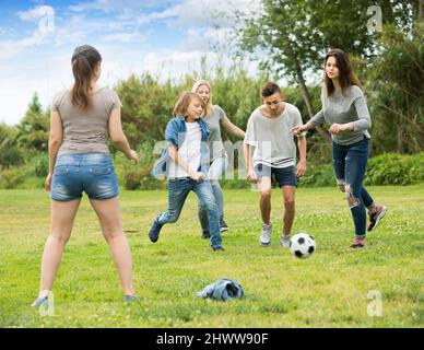 Des amis qui se sont mis à jouer au football dans le parc par beau temps Banque D'Images