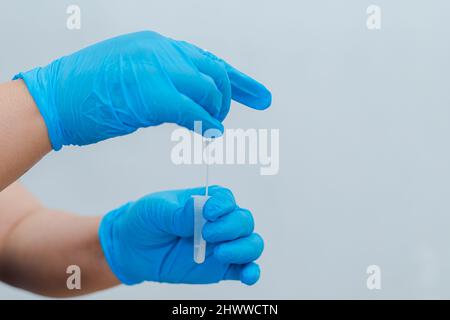 Une infirmière utilise un coton-tige trempé dans un kit de test d'antigène (ATK) comme kit de test pour COVID-19. Banque D'Images