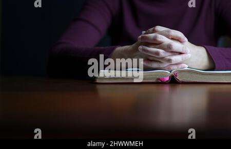 Les mains de la femme dans la posture de la prière au-dessus de la bible ouverte. Copier l'espace. Banque D'Images