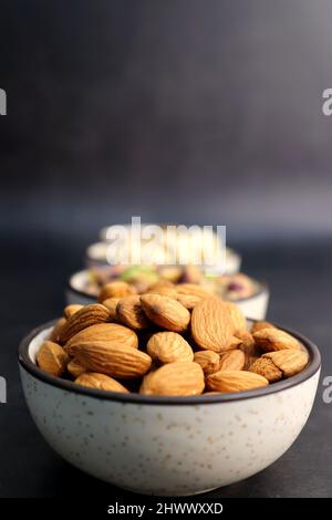 Diverses variétés de noix et de fruits secs sont dans un bol sur fond noir. Vue de dessus. Une alimentation saine. Nutrition végétarienne. noix de cajou, amande, pistache Banque D'Images