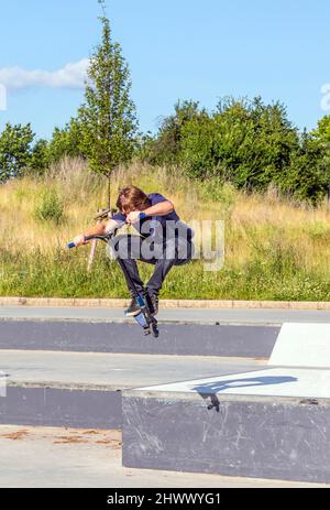 Garçon a fun riding push son scooter à la skatepark Banque D'Images