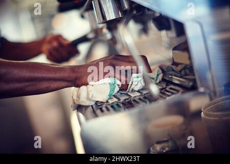 Prendre soin de sa machine à espresso. Gros plan d'un barista nettoyant une machine à espresso dans un café. Banque D'Images