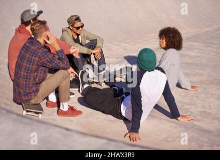 La joie langoureuse d'être os inactif. Photo d'un groupe d'amis assis au soleil dans un parc de skate. Banque D'Images