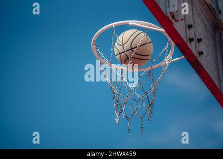 Basket-ball Shot tombant à travers le Net avec l'arrière-plan Blue Sky. Banque D'Images