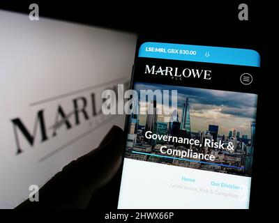 Personne tenant un téléphone portable avec la page Web de la société britannique de conformité Marlowe plc à l'écran devant le logo. Concentrez-vous sur le centre de l'écran du téléphone. Banque D'Images