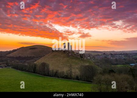 Corfe Castle Dorset, Royaume-Uni. 8th mars 2022. Météo Royaume-Uni. Un lever de soleil spectaculaire tandis que les nuages brillent orange au-dessus des ruines du château de Corfe à Dorset, un matin froid et venteux. Crédit photo : Graham Hunt/Alamy Live News Banque D'Images