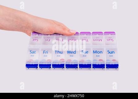 Femme main tenant des pilules boîte. Organiseur portable en plastique pour tablettes et vitamines. Soins de santé à domicile et pendant les voyages. Photo de haute qualité Banque D'Images