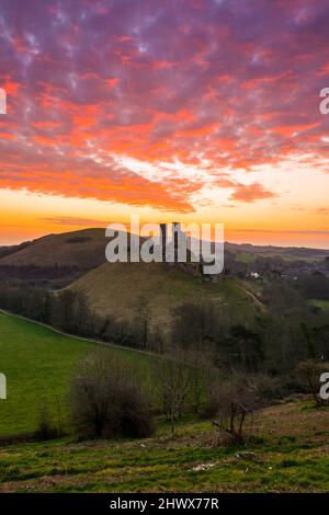 Corfe Castle Dorset, Royaume-Uni. 8th mars 2022. Météo Royaume-Uni. Un lever de soleil spectaculaire tandis que les nuages brillent orange au-dessus des ruines du château de Corfe à Dorset, un matin froid et venteux. Crédit photo : Graham Hunt/Alamy Live News Banque D'Images