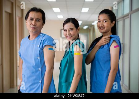 Le personnel médical se montrant bandage avec du plâtre sur le bras après avoir été atteint contre le vaccin Covid-19, une infirmière heureuse et un homme debout à l'hôpital, Covid Banque D'Images