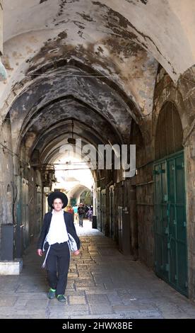 Un garçon juif Yeshiva marchant dans la rue Al-Wad dans le quartier musulman de la vieille ville de Jérusalem. Banque D'Images