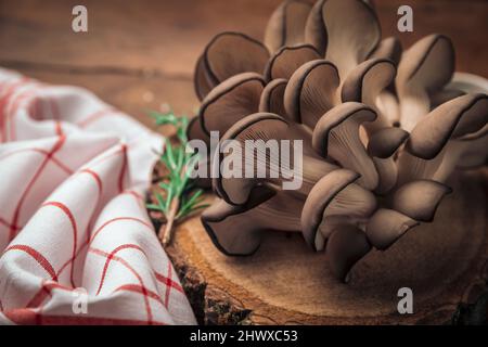 gros plan de champignons d'huîtres sur une planche à découper en bois antique et une serviette de cuisine favorisant un mode de vie sain Banque D'Images