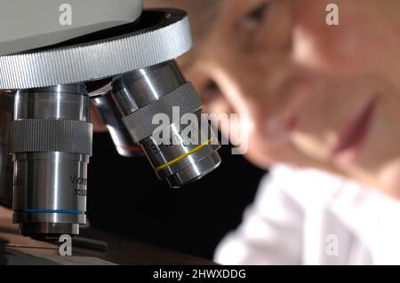 Étudiant en sciences utilisant un microscope pour analyser des échantillons biologiques. (MODÈLE DISPONIBLE) Banque D'Images