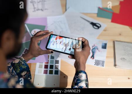 Au-dessus de l'angle du jeune homme créatif avec smartphone prenant des photos de ses collages compilés d'éléments coupés des images Banque D'Images