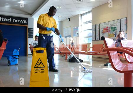 Un nettoyant hospitalier, en nettoyant le sol dans la zone de réception de l'hôpital.(MODÈLE RELÂCHÉ) Banque D'Images