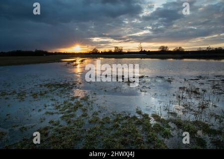 Nuages et coucher de soleil sur la prairie inondée et gelée Banque D'Images