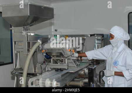 Assistant pharmaceutique surveillant une unité de dispersion de pilules. Banque D'Images