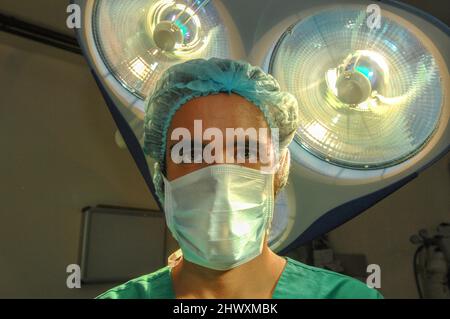 Un chirurgien masqué se tient sous un ensemble d'éclairages de la salle d'opération (MODÈLE RELÂCHÉ) Banque D'Images