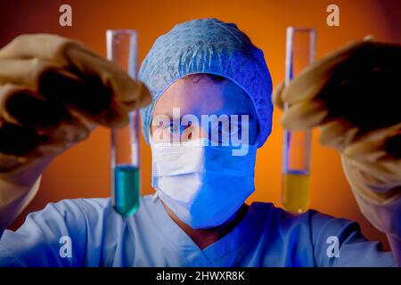 Un technicien de laboratoire tenant deux tubes à essai contenant chacun un liquide coloré.(MODÈLE RELÂCHÉ) Banque D'Images