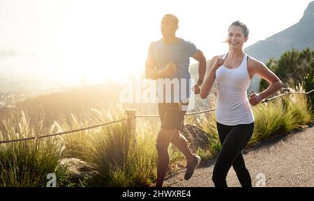 Certains l'appellent courir, nous l'appelons la vie. Photo d'un couple sportif qui court sur une route de montagne. Banque D'Images