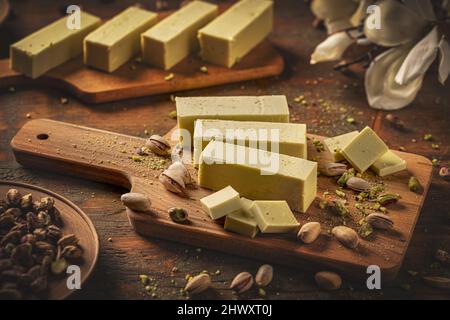 Fudge au chocolat blanc végétalien brut avec pistache sur une planche de bois. Concept alimentaire végétalien sain. Banque D'Images