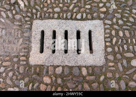 Ancien drain d'eau en pierre dans une rue pavée, vue de dessus Banque D'Images