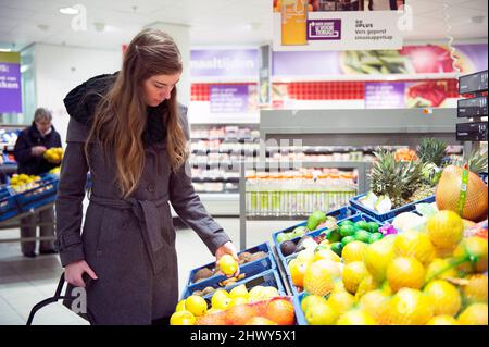 Tilburg, pays-Bas., jeune femme adulte visitant le supermarkt local acheter et acheter de la nourriture et des provisions pour un style de vie sain. Banque D'Images