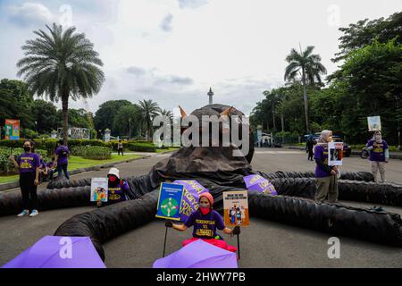 Jakarta, Indonésie. 08th mars 2022. Les activistes tiennent des pancartes à côté d'une sculpture représentant un poulpe sur le thème de l'oligarchie lors de la manifestation à l'occasion de la Journée internationale de la femme. Les militantes se rassemblent à l'occasion de la Journée internationale de la femme dans la région de Monas, à Jakarta. La masse demande au gouvernement de mettre en œuvre un système de protection sociale qui ne fait pas de discrimination à l'égard des femmes. Crédit : SOPA Images Limited/Alamy Live News Banque D'Images