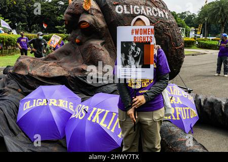 Jakarta, Indonésie. 08th mars 2022. Une militante tient un écriteau à côté d'une sculpture représentant un poulpe sur le thème de l'oligarchie lors de la manifestation de la Journée internationale de la femme.les militantes se rassemblent à l'occasion de la Journée internationale de la femme dans la région de Monas, à Jakarta. La masse demande au gouvernement de mettre en œuvre un système de protection sociale qui ne fait pas de discrimination à l'égard des femmes. Crédit : SOPA Images Limited/Alamy Live News Banque D'Images