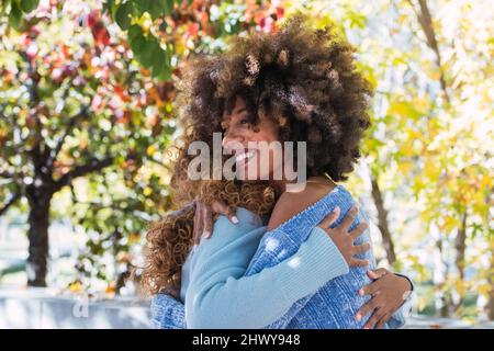 Portrait de deux amies afro-américaines heureuses qui s'embrasent les unes les autres et rient dans le parc. Joyeux amis noirs afro donnant chaud câlin Banque D'Images