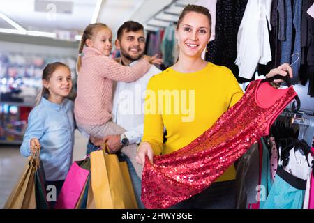 Une jeune mère choisit une nouvelle robe en magasin Banque D'Images