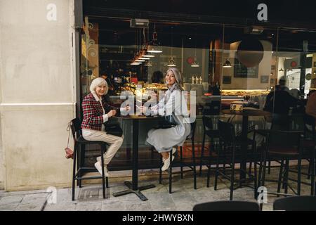 Des amies urbaines qui apprécient la conversation dans un café Banque D'Images