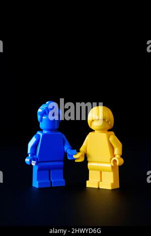 Deux caractères Lego, l'un bleu et l'autre jaune, tenant les mains. Les couleurs représentent le drapeau ukrainien pour montrer la solidarité pendant la guerre actuelle Banque D'Images