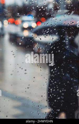 Silhouette floue de fille avec parapluie sur la rue de la ville vu par fenêtre humide, la circulation de la ville, la rue urbaine Banque D'Images