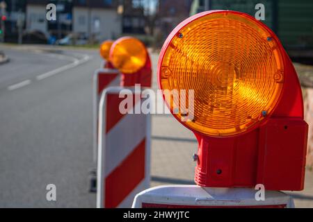 Barricade de rue avec témoin clignotant d'avertissement sur une route sécurité du chantier de construction, arrière-plan du chantier flou Banque D'Images