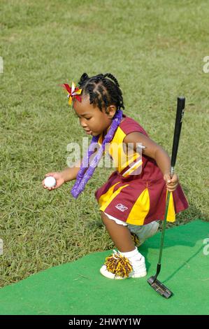 Jeune fille en uniforn cheerleaders jouer avec gold club et balle à l'événement de collecte de fonds pour les équipes de football Banque D'Images