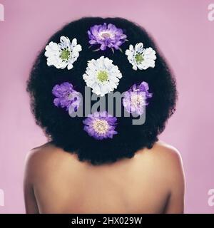 Les fleurs sont partout. Photo en vue arrière d'une femme debout avec des fleurs dans ses cheveux. Banque D'Images