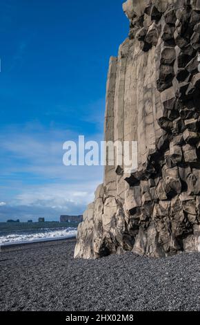 La célèbre plage de sable noir, le mont Reynisfjall et les pittoresques colonnes de Basalt, Vik, Islande du Sud. Le cap Dyrholaey et les formations rocheuses de loin. Banque D'Images