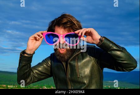 Homme barbu dans de grands verres. Drôle de gars dans de grandes lunettes. Taille basse en cuir veste et lunettes de soleil. Banque D'Images