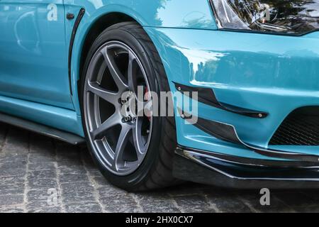 Gros plan sur une roue d'une voiture de sport. Jante de voiture grise avec caoutchouc bas profil. Voiture de sport bleue. Banque D'Images