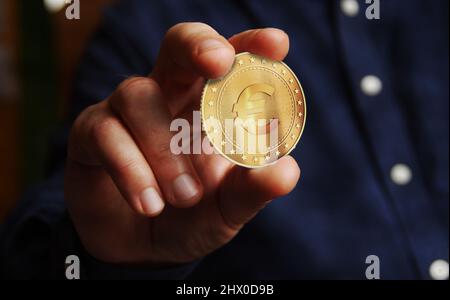 Euro devise EUR dans le symbole de l'UE pièce d'or à la main concept abstrait. Banque D'Images
