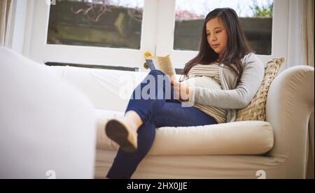 Le congé de maternité signifie un peu de temps pour elle pour se détendre. Photo d'une femme enceinte lisant un livre à la maison. Banque D'Images