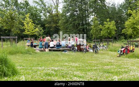 Kessel-Lo, Louvain Flandre - Belgique - 06 16 2019 - les familles avec leurs enfants mangent autour d'une grande table en bois au soleil Banque D'Images