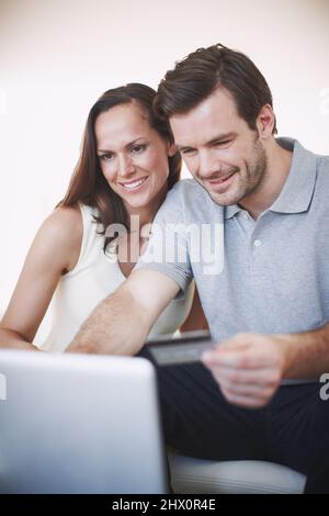 Banque en ligne : rapide et facile. Photo d'un jeune homme faisant ses opérations bancaires en ligne pendant que sa femme est assise à côté de lui. Banque D'Images