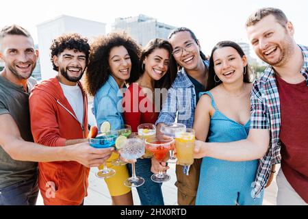 Des gens multiraciaux se savourent des cocktails branchés sur le toit pendant les vacances d'été Banque D'Images