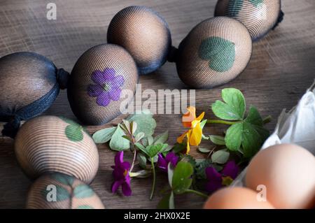 Oeufs de Pâques décorés de feuilles et de fleurs, préparés pour la teinture naturelle avec des peaux d'oignons Banque D'Images