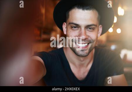 Souriez si vous êtes un client satisfait. Portrait d'un beau jeune homme prenant un selfie dans un café. Banque D'Images