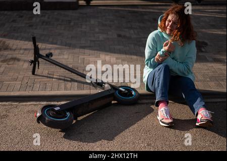 Une femme de race blanche est tombée d'un scooter électrique et a blessé son bras.Souffrant de douleur. Banque D'Images