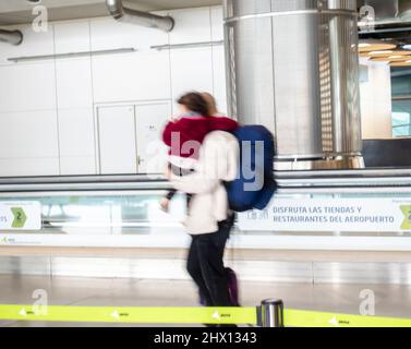 Un homme marchant avec un enfant en mouvement flou dans le terminal des départs, aéroport de Madrid-Barajas, Espagne Banque D'Images