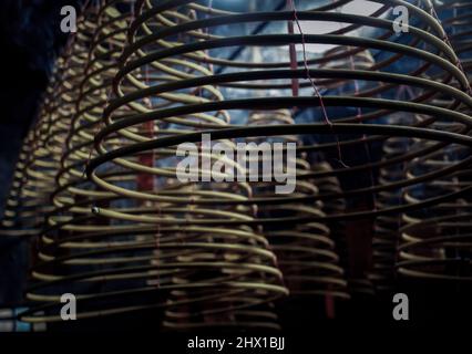 Plusieurs grandes bobines d'encens jaunes suspendues en piles du plafond dans un sanctuaire chinois. Grandes bobines d'Encens en spirale en forme de cloche, mise au point et flou. Banque D'Images